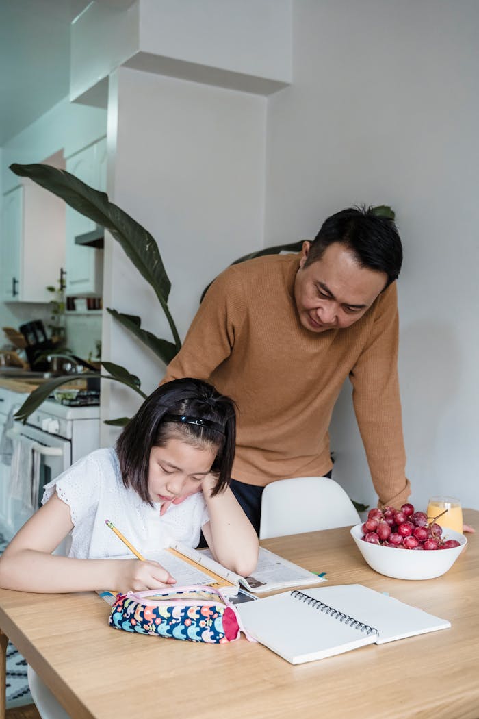Father helping daughter with homework in kitchen setting, fostering education and family bonding.